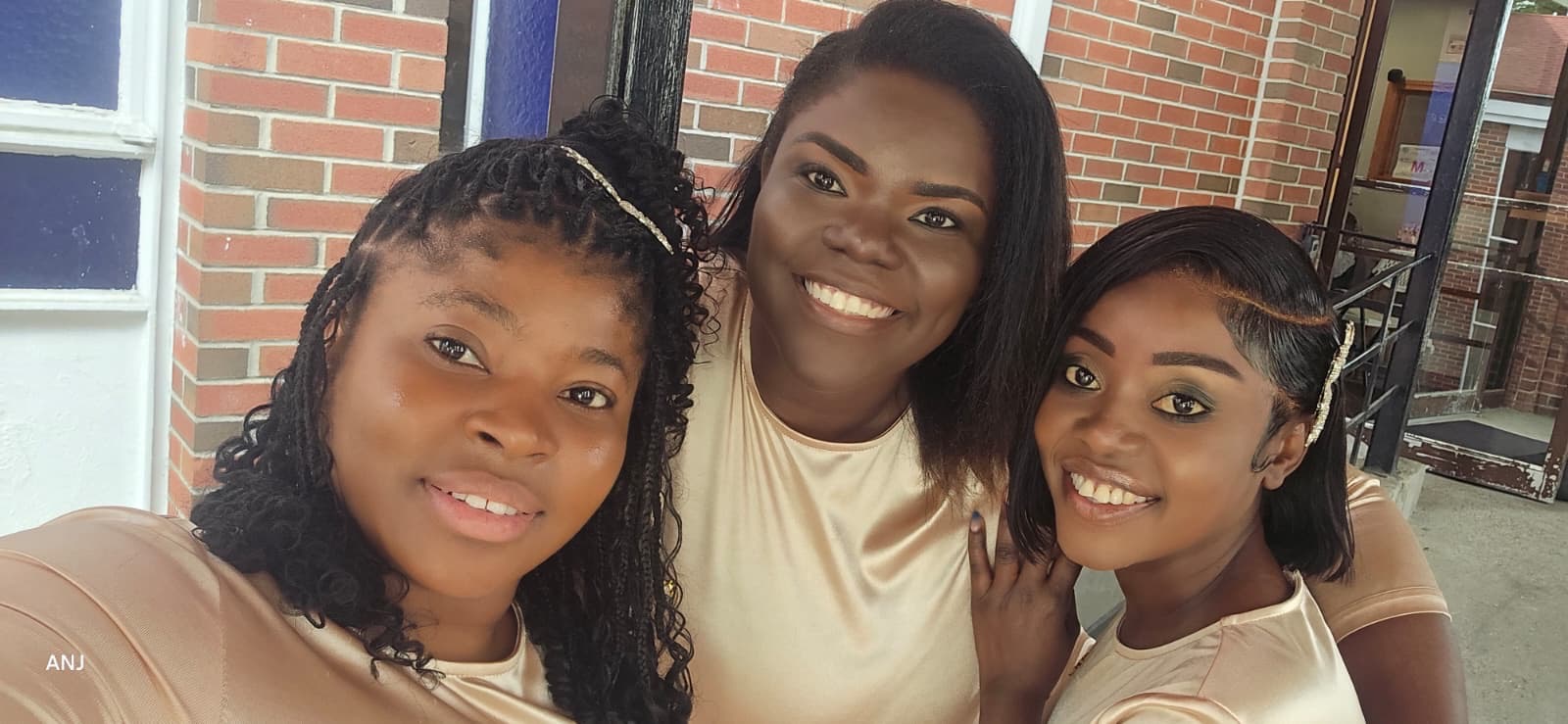 Close-up of three smiling MAS-B Vocal Ministry members in champagne gowns