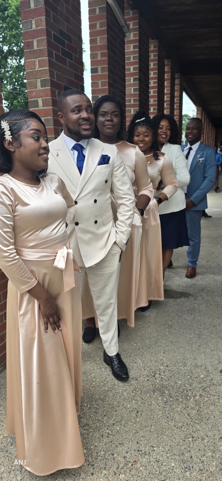 MAS-B Vocal Ministry ensemble in champagne gowns and suits lined up along a church walkway