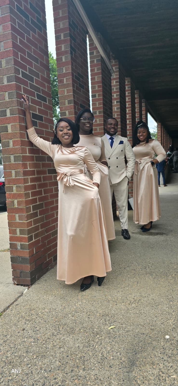 MAS-B singers and a minister in champagne attire beside brick columns at church