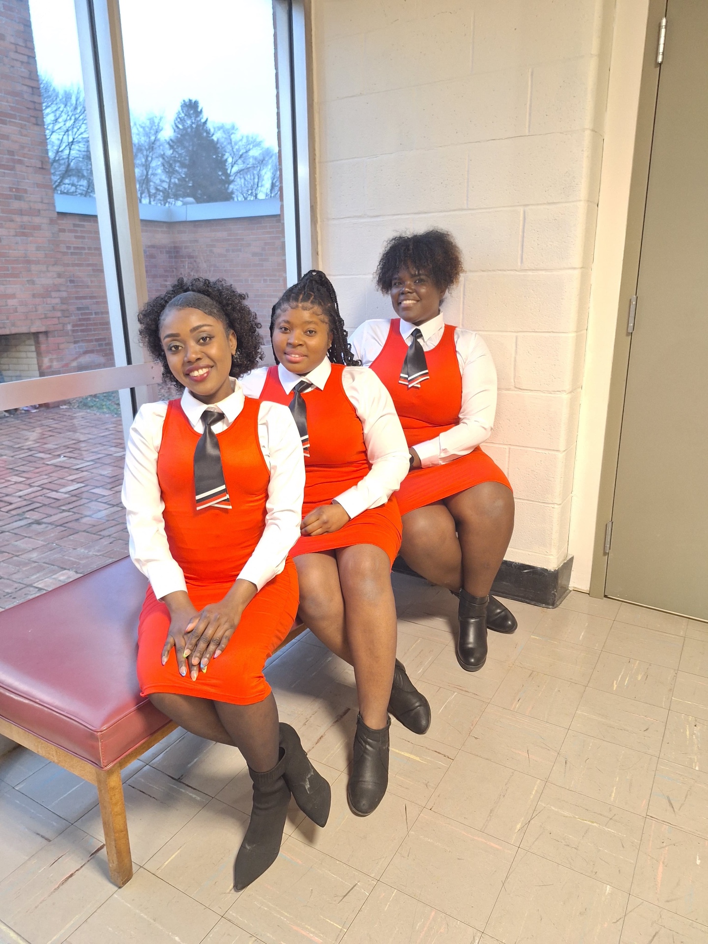 MAS-B Vocal Ministry members in red uniforms seated by a sunlit church window