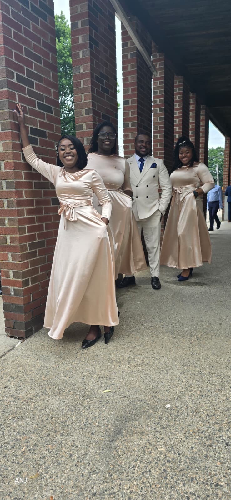 MAS-B Vocal Ministry members in champagne attire along a brick church walkway