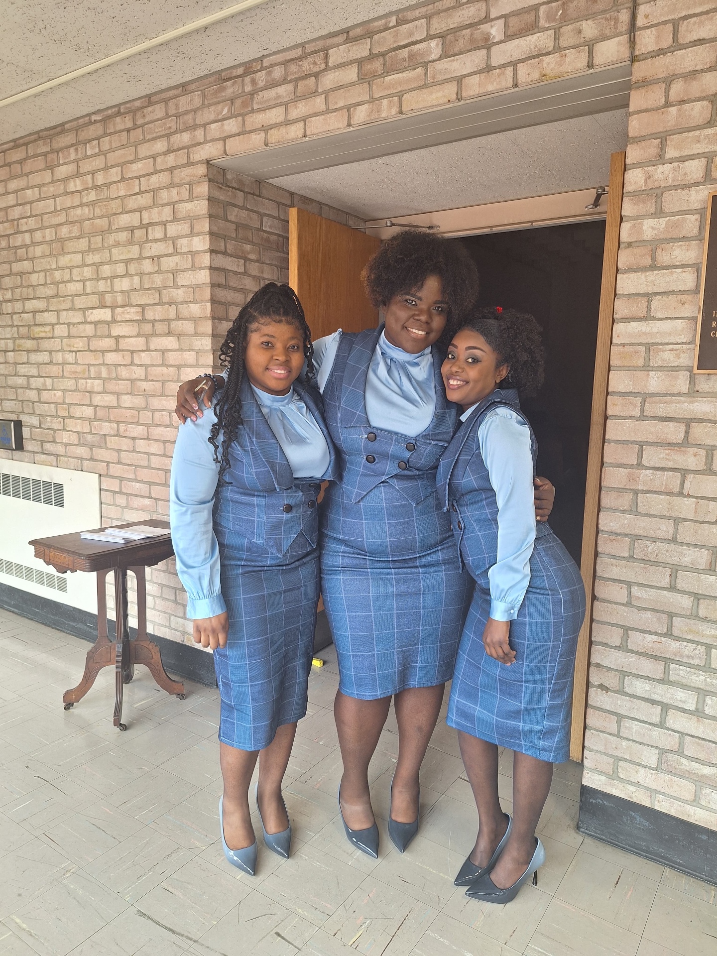 Three MAS-B Vocal Ministry members embracing at the chapel doorway