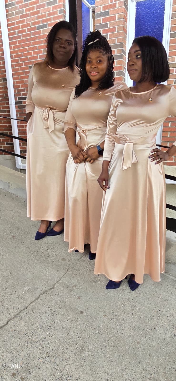 Three MAS-B Vocal Ministry members posing in champagne gowns by the chapel doors